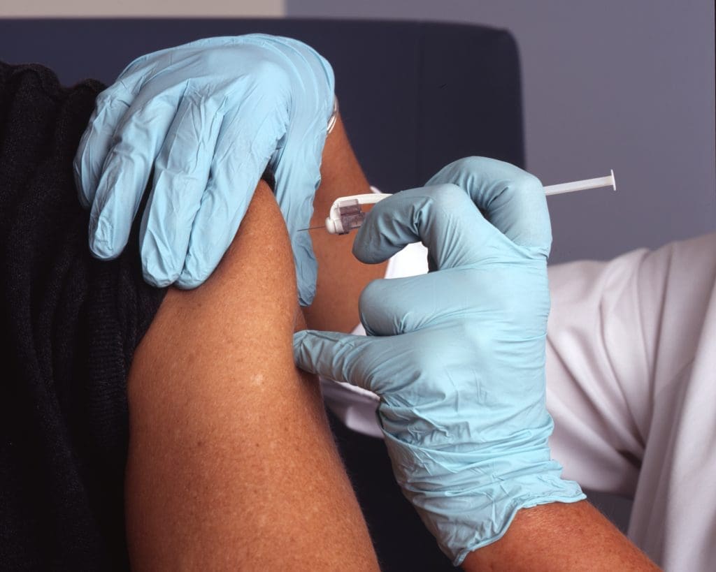 Glove-handed doctor administers a vaccine to an adult